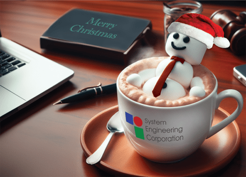 Executive holiday card featuring your own full color logo on a mug sitting on a desk. A cheerful marshmallow man with a Santa hat is lounging in the cocoa.